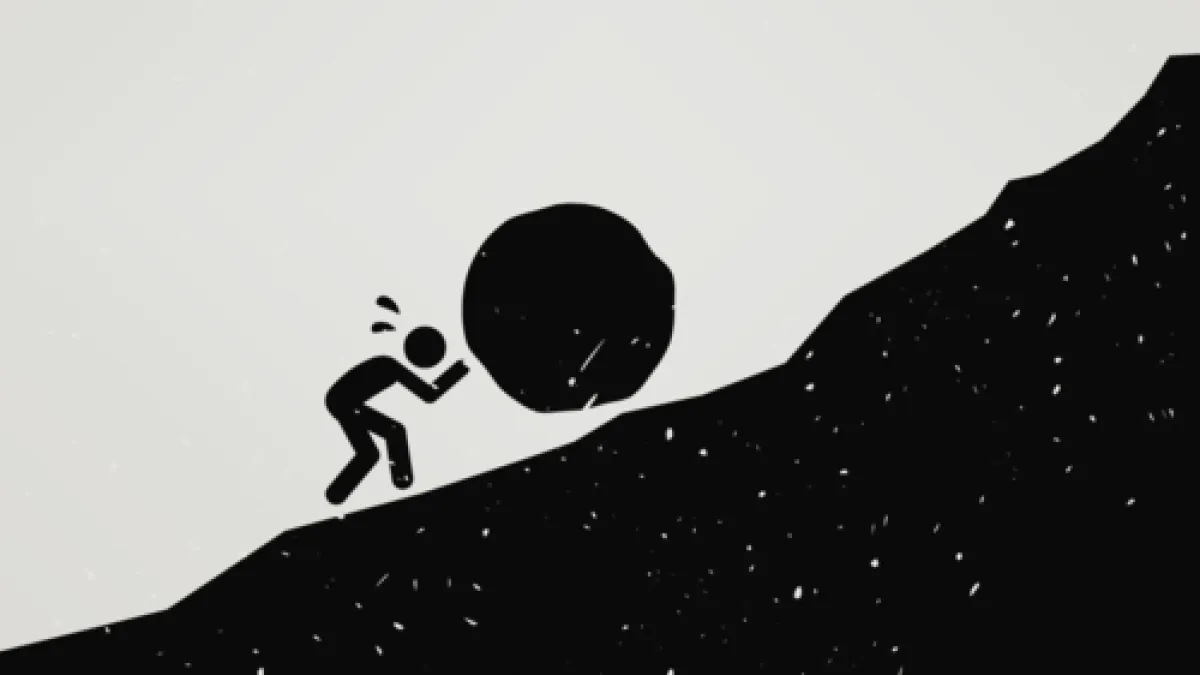 Silhouette of a person pushing a huge boulder up a steep hill