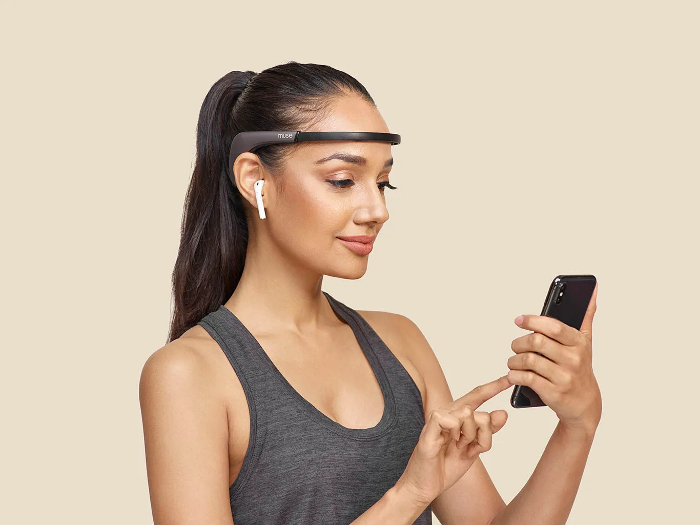 A woman wearing the Muse 2 meditation headband while using her phone
