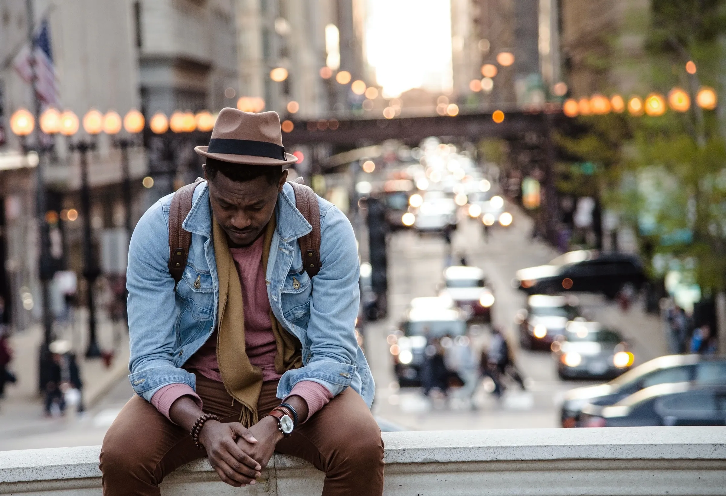 A man sitting alone with his head down on a busy city street