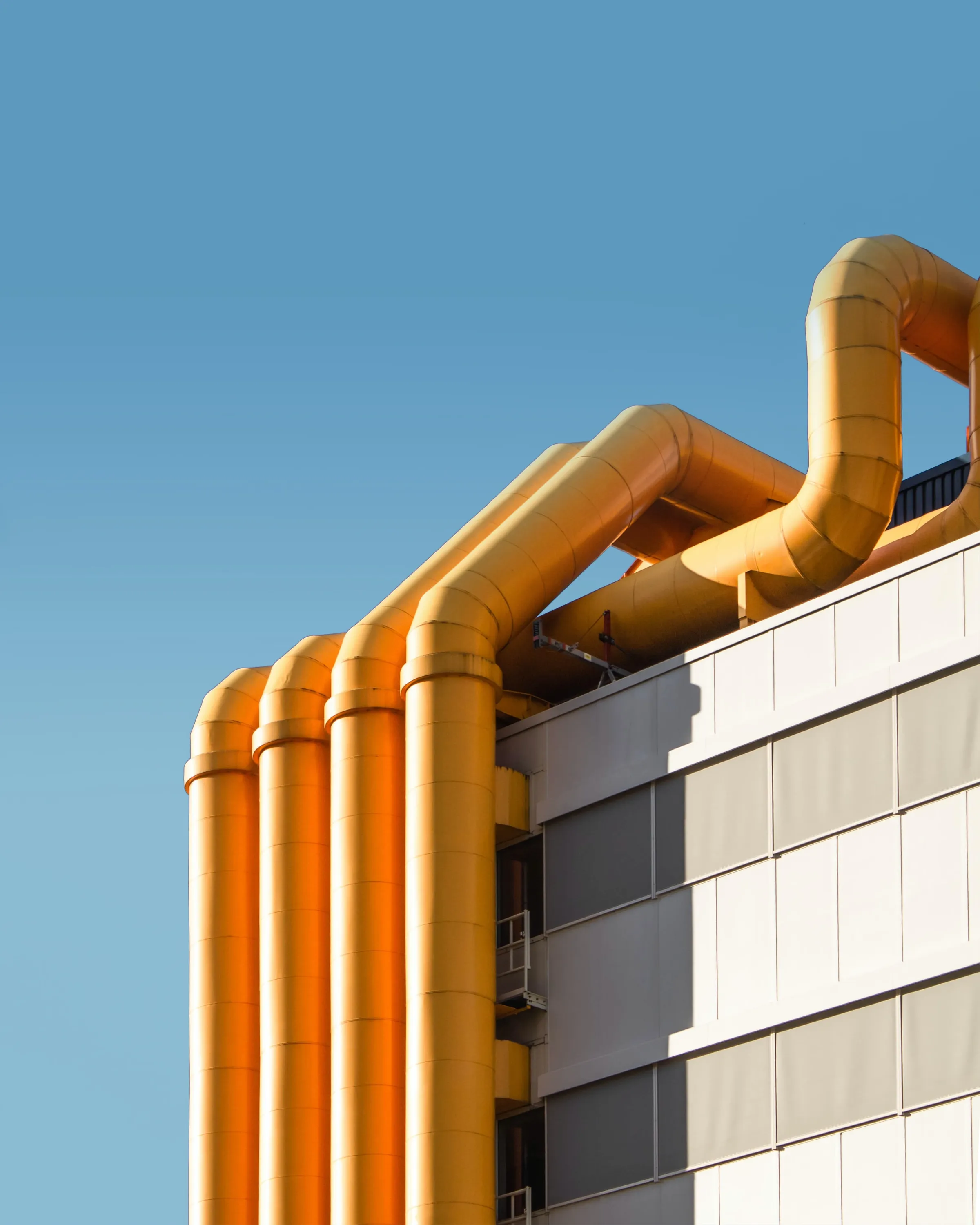 Orange industrial pipes running up the side of a building