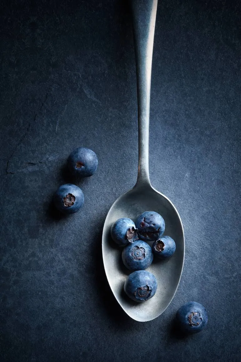 Blueberries in a silver spoon on a dark background