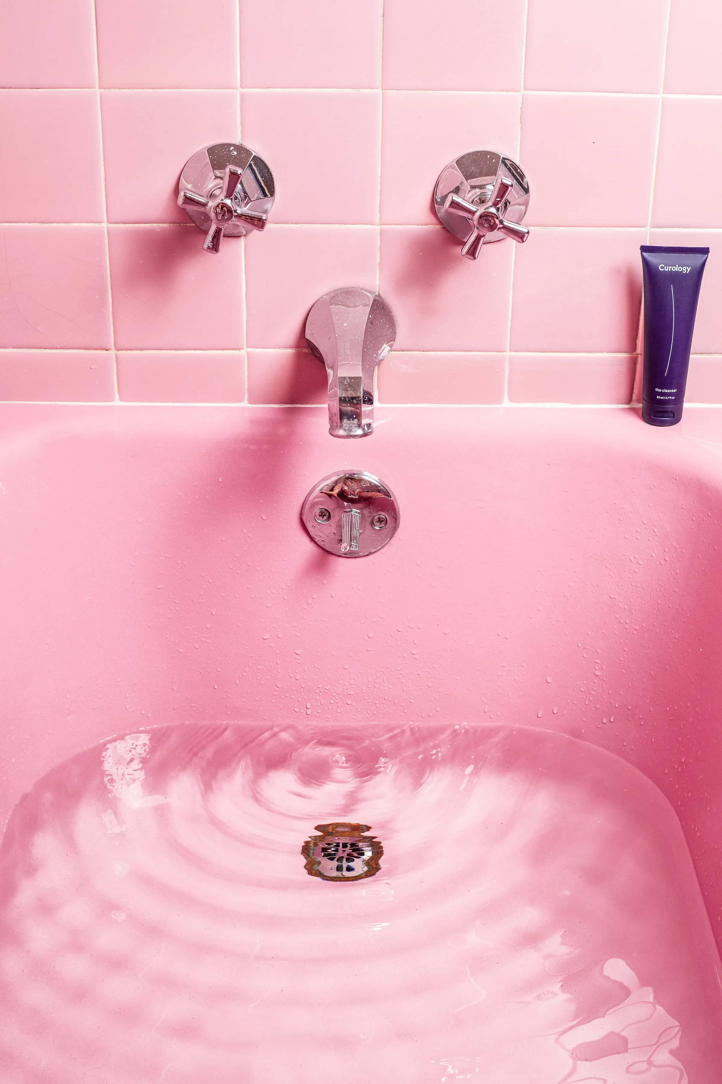 A pink bathtub filling with water